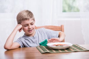 How to help your picky eaters - a young boy pushes away a plate of food