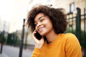 happy-african-american-young-woman-talking-with-cellphone-in-city