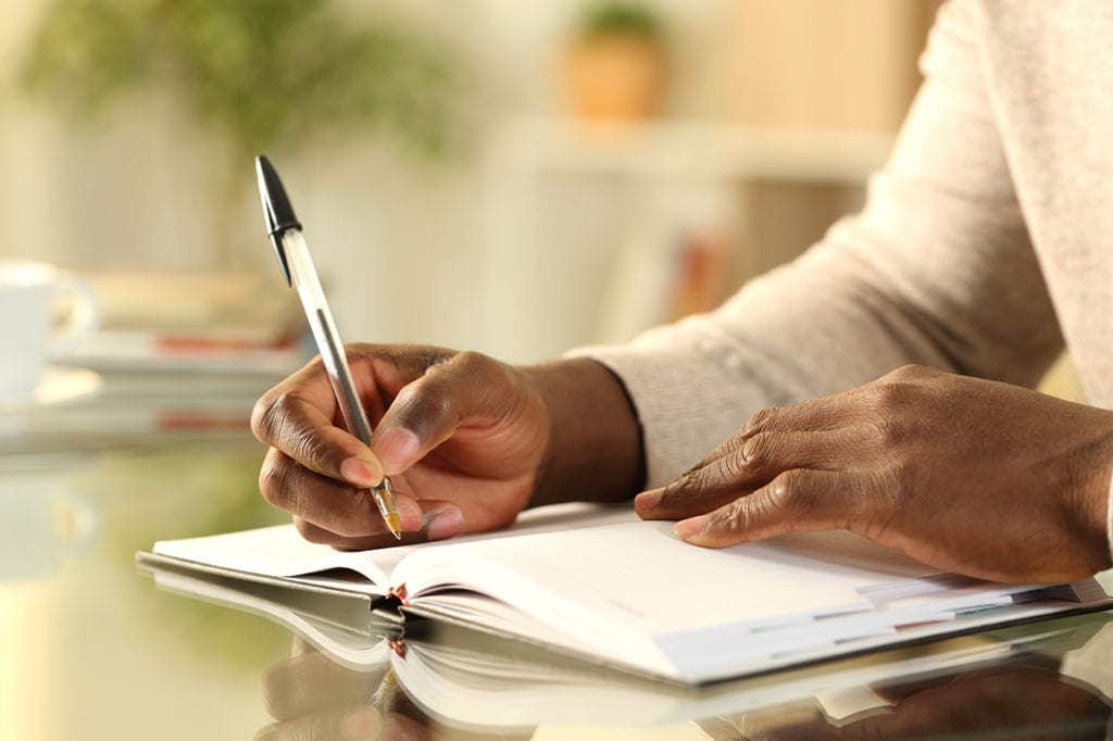 health and wellness coach writing down niche ideas in a notebook with a pen