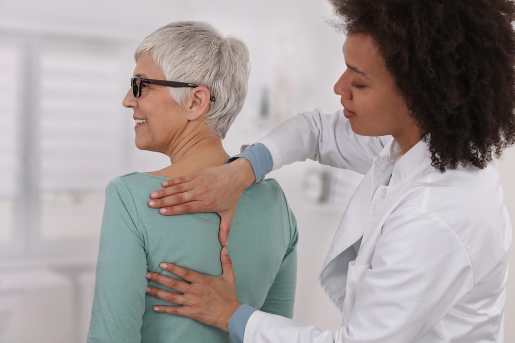 What is Holistic Health and What are Its Pillars? 8 Mature Woman having chiropractic back adjustment. Osteopathy, Physiotherapy, Sport injury rehabilitation concept, holistic care