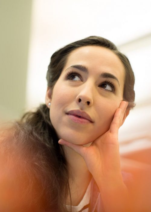 Thoughtful young businesswoman looking away while sitting in office