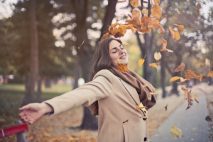 wellness tips for an abundant fall - woman throwing leaves into air